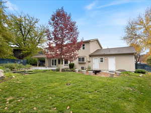 Back of property with fence, a lawn, and a patio