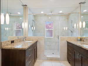 Full bath with a stall shower, a sink, tile walls, and tile patterned floors