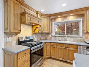 Kitchen with stainless steel appliances, recessed lighting, decorative backsplash, a sink, and light wood-type flooring