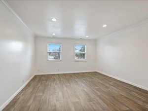 Spare room featuring crown molding, baseboards, wood finished floors, and recessed lighting