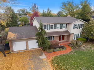 Traditional-style home featuring brick siding, a porch, a shingled roof, a front yard, and driveway