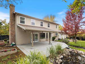 Back of property with a chimney, a patio area, fence, and a garden