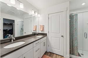 Bathroom featuring double vanity, a sink, visible vents, and a shower stall