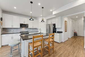 Kitchen with appliances with stainless steel finishes, dark countertops, a sink, and decorative backsplash