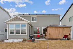 Rear view of house featuring a patio area, fence, a lawn, and stucco siding