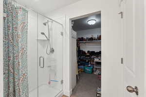 Bathroom with a walk in closet and a shower stall