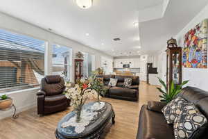 Living room with light wood-type flooring, visible vents, and baseboards