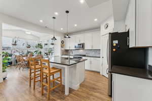 Kitchen featuring white cabinets, dark countertops, appliances with stainless steel finishes, a breakfast bar, and backsplash