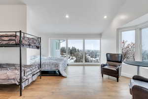 Bedroom with vaulted ceiling, baseboards, wood finished floors, and recessed lighting