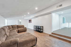 Living area featuring a textured ceiling, wood finished floors, visible vents, and recessed lighting