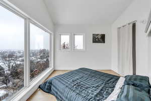 Bedroom with lofted ceiling, light wood-type flooring, and baseboards