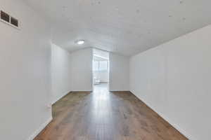 Bonus room featuring lofted ceiling, hardwood / wood-style floors, visible vents, and baseboards