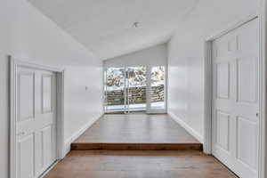 Interior space with lofted ceiling, a textured ceiling, baseboards, and hardwood / wood-style flooring