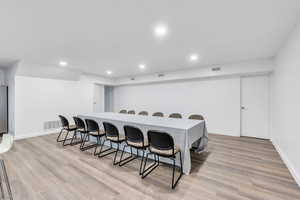 Interior space featuring light wood-type flooring, visible vents, a kitchen breakfast bar, and recessed lighting