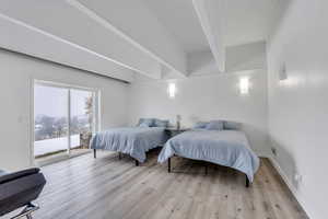 Bedroom featuring access to outside, baseboards, beam ceiling, and wood finished floors