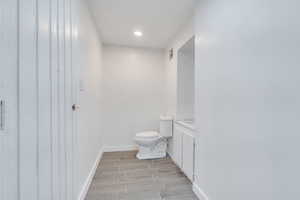 Bathroom with wood finish floors, baseboards, and toilet