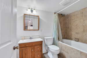 Full bath with tiled shower / bath combo, visible vents, toilet, and vanity