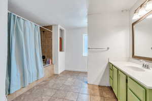 Bathroom featuring tile patterned flooring, shower / bath combination with curtain, vanity, and baseboards