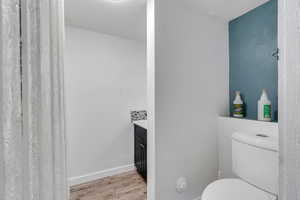 Bathroom featuring toilet, vanity, baseboards, and wood finished floors