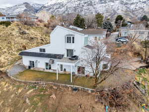 Back of property featuring roof with shingles, a mountain view, and a yard