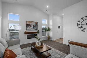 Carpeted living room with high vaulted ceiling, recessed lighting, and a cozy fireplace