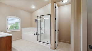 Full bath featuring a bath, vanity, baseboards, a stall shower, and lofted ceiling