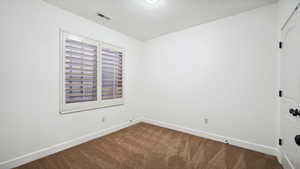 Carpeted bedroom with a textured ceiling, visible vents, and baseboards