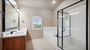 Full bathroom featuring a garden tub, a sink, lofted ceiling, and baseboards