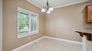 Unfurnished dining area featuring ornamental molding, a healthy amount of sunlight, visible vents, and a notable chandelier