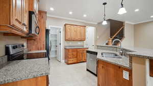 Kitchen featuring ornamental molding, a sink, decorative light fixtures, and appliances with stainless steel finishes