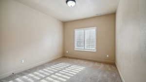 Carpeted spare room with visible vents and baseboards