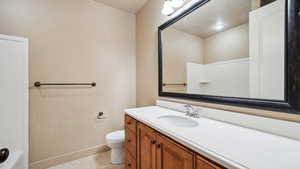 Bathroom with toilet, tile patterned flooring, vanity, and baseboards