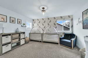 Bedroom with carpet floors, a nursery area, and visible vents