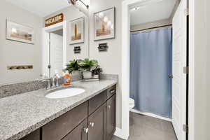 Full bath with toilet, curtained shower, tile patterned flooring, and vanity