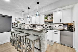 Kitchen with a breakfast bar area, open shelves, white cabinets, a peninsula, and fridge