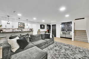 Living area with light wood-style floors, stairs, visible vents, and recessed lighting