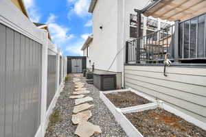 View of side of property with stairway, a vegetable garden, and fence