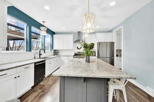 Kitchen featuring wall chimney exhaust hood, dark wood-style flooring, stainless steel appliances, and a sink