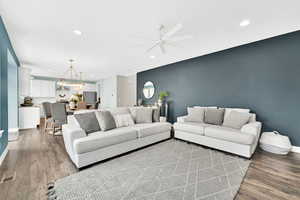 Living area with recessed lighting, an accent wall, wood finished floors, visible vents, and baseboards