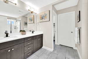 Bathroom with double vanity, a stall shower, baseboards, and a sink