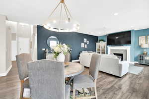 Dining room featuring a brick fireplace, ceiling fan, baseboards, and wood finished floors