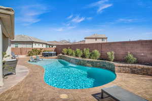 View of swimming pool featuring a hot tub, a patio area, a fenced backyard, and a fenced in pool