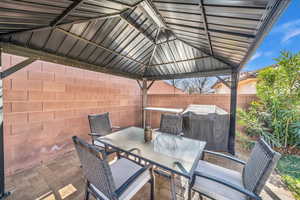 View of patio featuring outdoor dining area, a grill, and fence