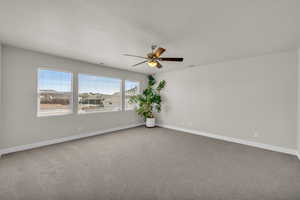 Empty room with carpet, a ceiling fan, and baseboards