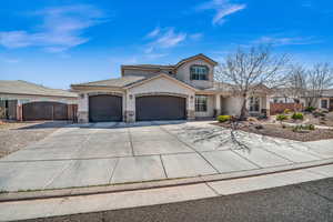 View of front of home with a garage, stone siding, fence, and a gate