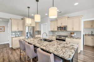 Kitchen featuring visible vents, appliances with stainless steel finishes, cream cabinetry, and a sink