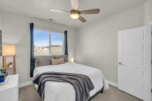 Bedroom featuring light carpet, ceiling fan, visible vents, and baseboards