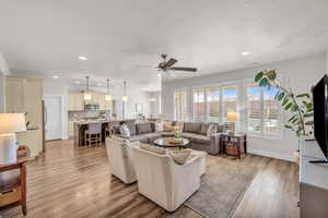 Living area featuring light wood-type flooring, baseboards, a ceiling fan, and recessed lighting