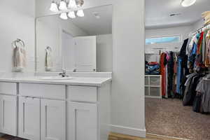 Bathroom with visible vents, a walk in closet, a textured ceiling, and vanity