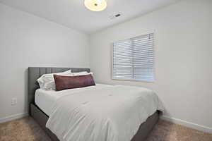 Carpeted bedroom featuring baseboards, visible vents, and a textured ceiling